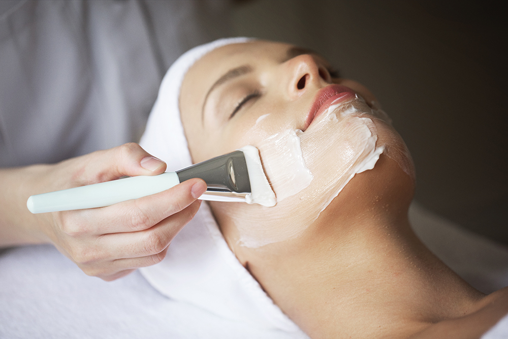 Female Therapist Applying Facial Mask On Woman's Face In Spa