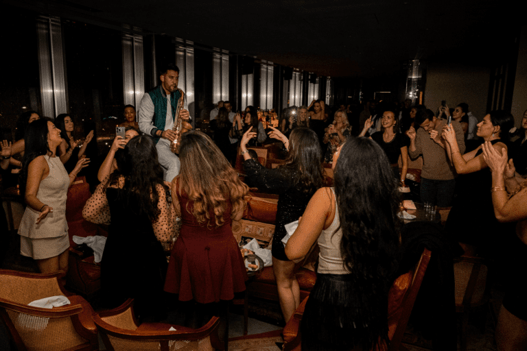 Un saxophoniste jouant en live au TOO TacTac Skybar, entouré de clients profitant d'une ambiance festive dans un cadre élégant.