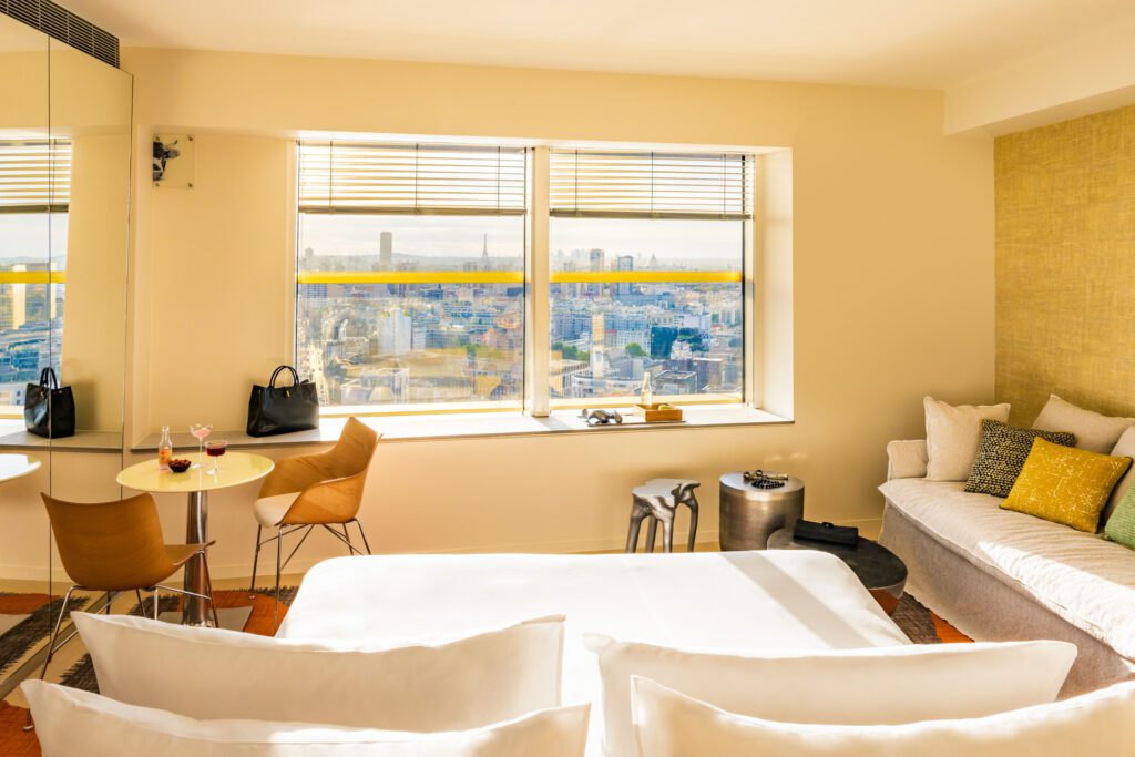 Chambre lumineuse du TOO Hôtel avec une vue panoramique sur Paris et la Tour Eiffel.